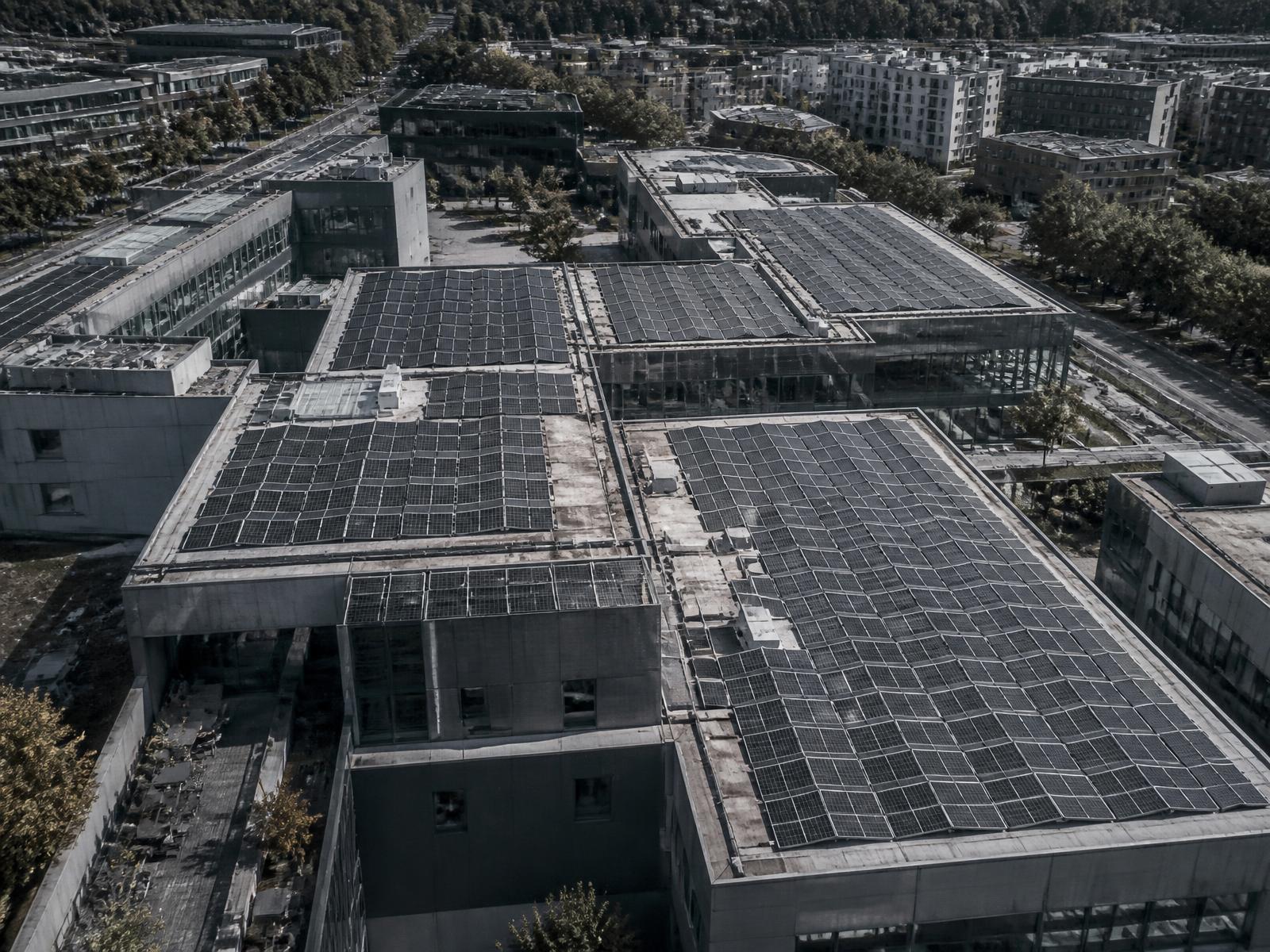 Aerial view of commercial rooftop solar arrays across a modern building complex